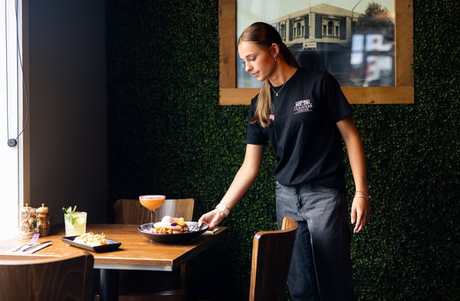 A woman placing a plate of food on a table.