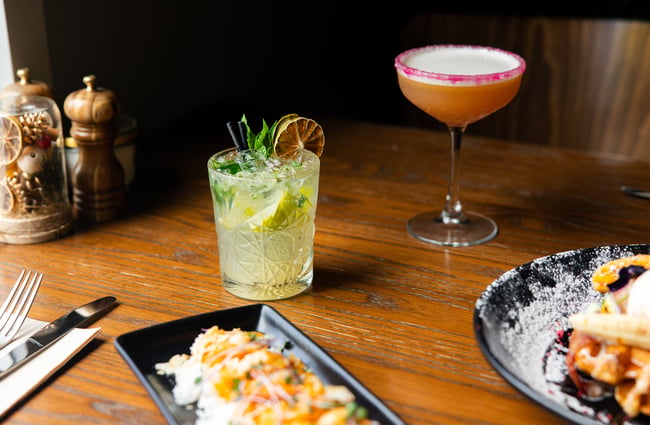 Food and cocktails beautifully displayed on a wooden table.