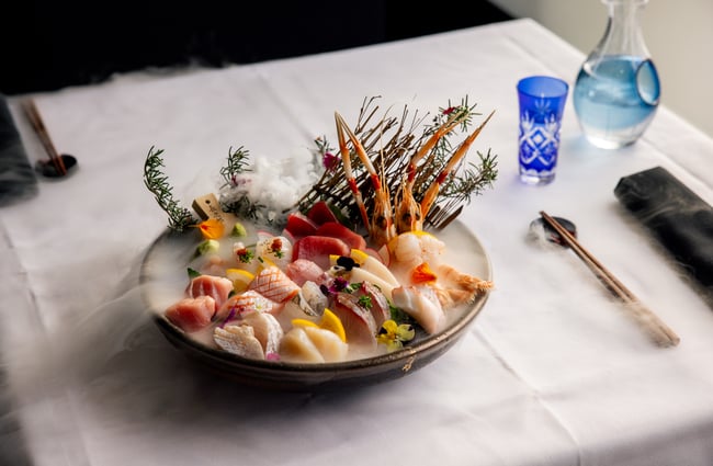 A close up of an exotic plate of seafood on a white table cloth.