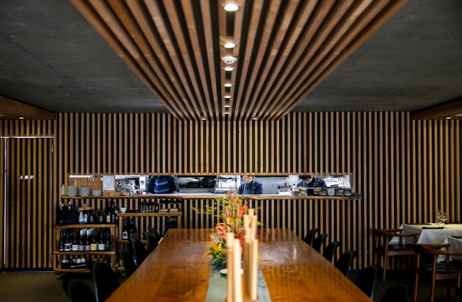 The long shared table inside a dimly lit restaurant.