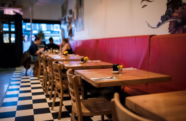 Wooden tables and chairs with red booth seating.