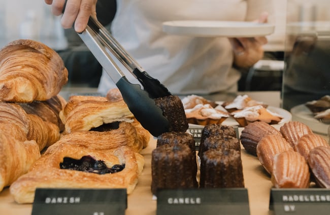 Tongs reaching for canele dessert in cabinet at Coffee Embassy Cashel Street in Christchurch
