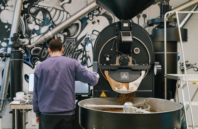 A staff member pouring coffee beans into a bag.