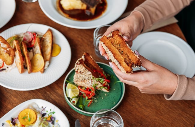 Diner holding a sandwich at Commons Eatery.