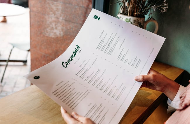 Someone reading a menu at Commons Eatery.
