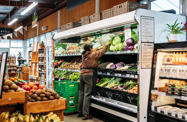 Shop assistant reaching into fresh produce fridge at Commonsense Organics in Kilbernie