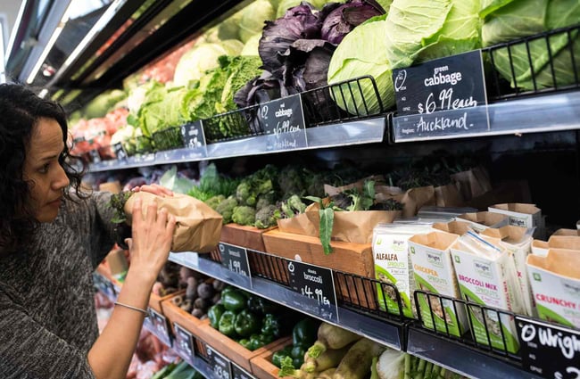 Looking at vegetables on a wooden shelf.