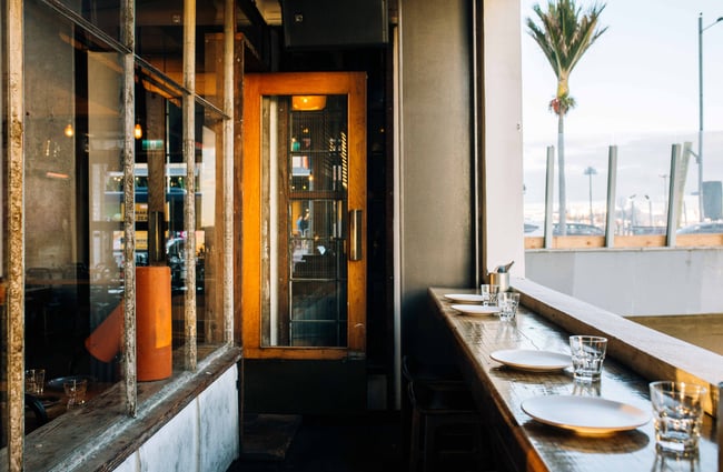Bench top dining with palm tree in the background at Otto, Auckland.