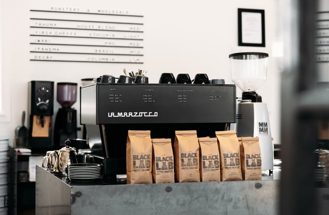 Bags of.coffee beans sitting next to a coffee machine.