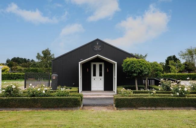 Building exterior of Country Road High Tea surrounded by gardens.