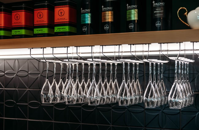 Champagne glasses are lined up on a shelf with a row of teas above them at Country Road High Tea.