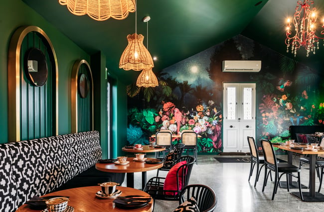 Seating area up against the wall in the dining room with chandeliers overhead at Country Road High Tea.