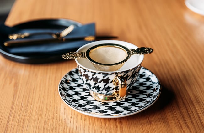A houndstooth patterned tea cup and saucer sits on the table.