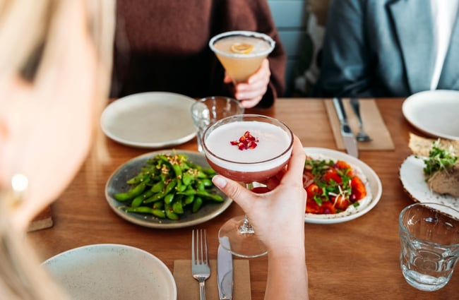 A hand holding a pink cocktail.