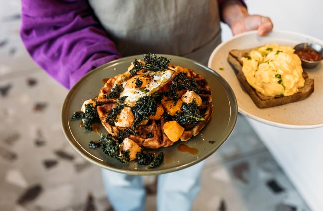 Close up of waitstaff holding a plate of savoury waffles at Cream Eatery in Hamilton.