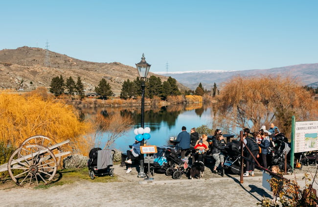 A group of cyclists by a lake on a sunny day.
