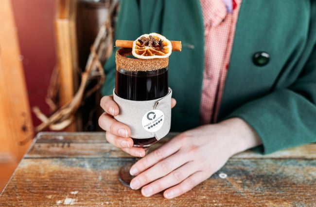 A close up of a hold handing a glass of mulled wine.