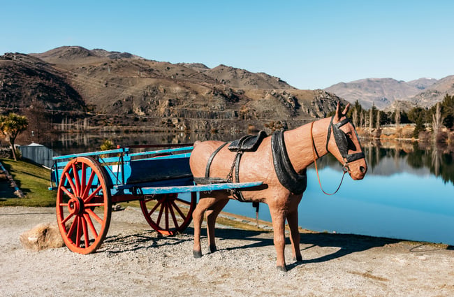 A wooden horse and carriage by a lake.