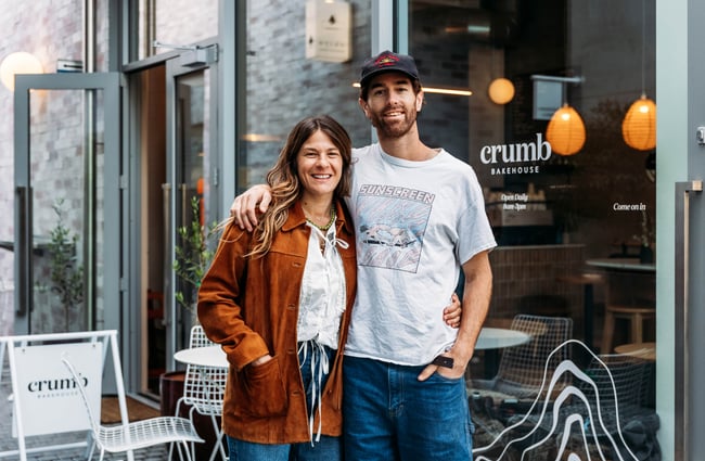 A couple stands outside the building of Crumb.
