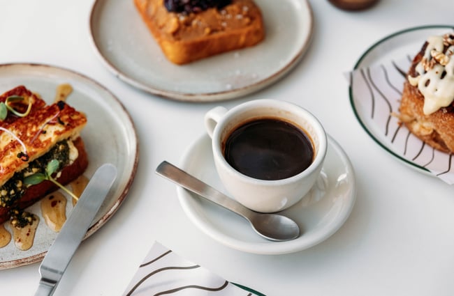 A cup of coffee in the centre of the table surrounded by food dishes at Crumb.