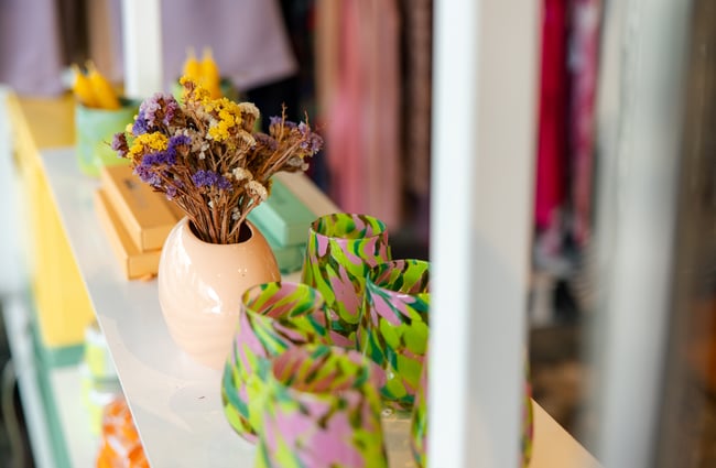 Close-up of dried flowers in a vase and colourful blown glass tumblers on display at Crushes.