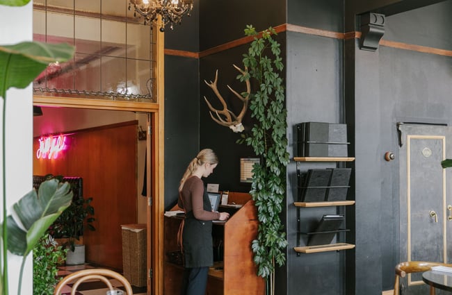A worker standing at the machine putting in a food order for a table.