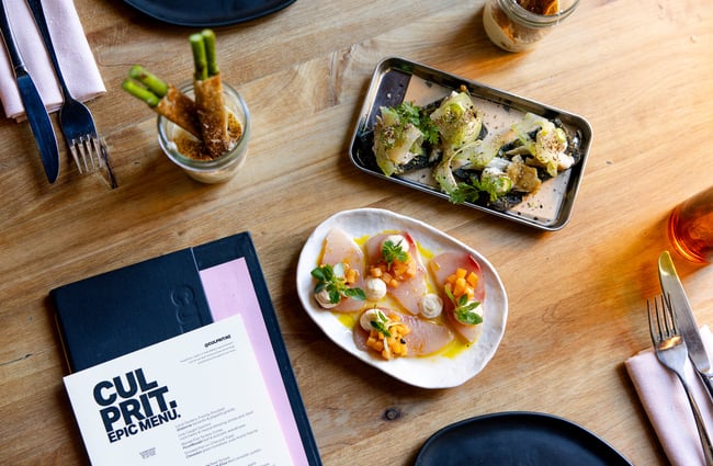 Plates of food next to a menu that sees 'Culprit' in black and white.