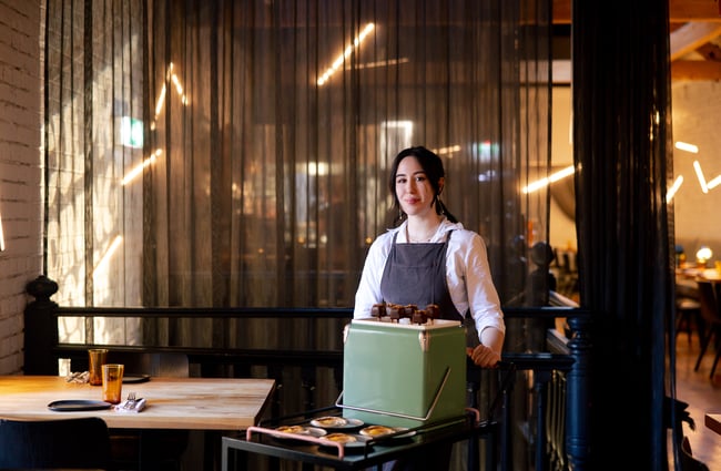A staff member standing next to a food trolley looking to camera.