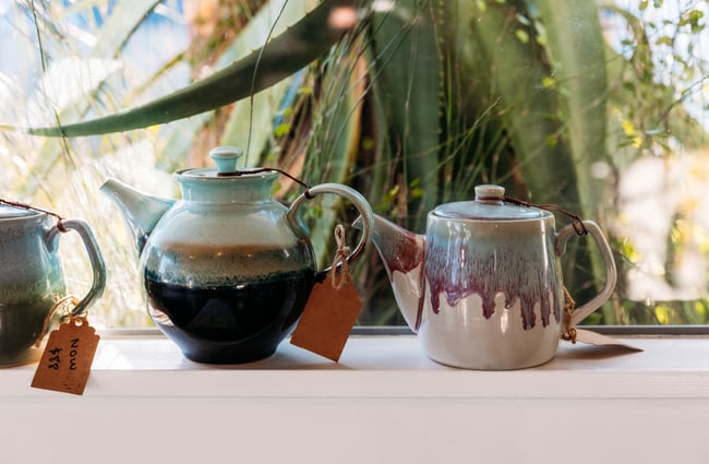 Two tea pots on display on a window sill.