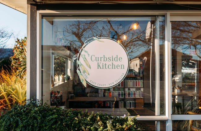 A 'Curbside Kitchen' sign on a glass window.
