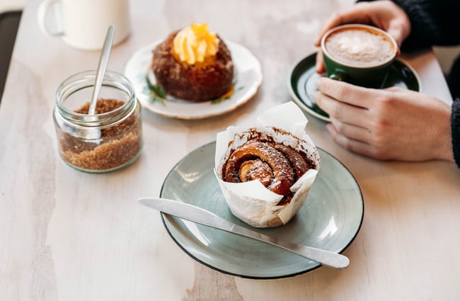 A coffee and two cakes on a table.