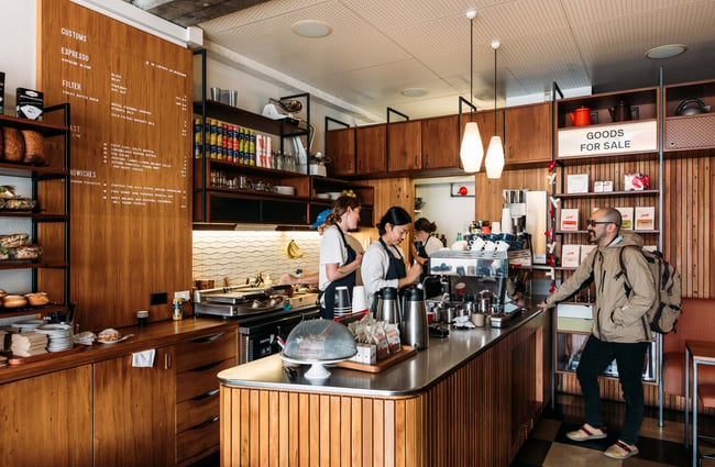 A customer chatting to staff members inside a cafe.