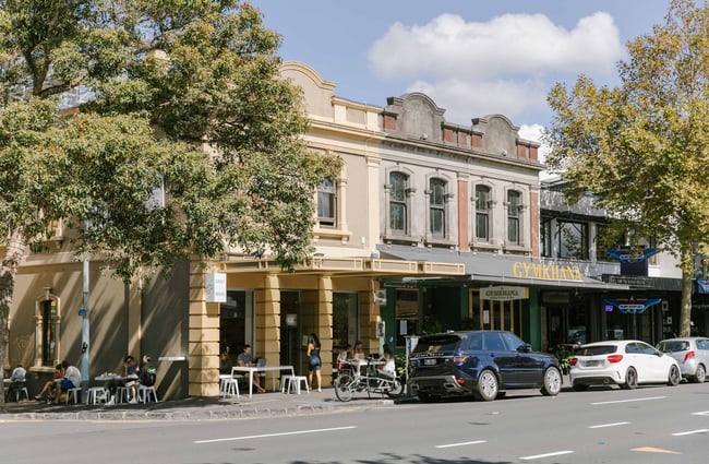 A view of a block of shops from across the street on a sunny day.