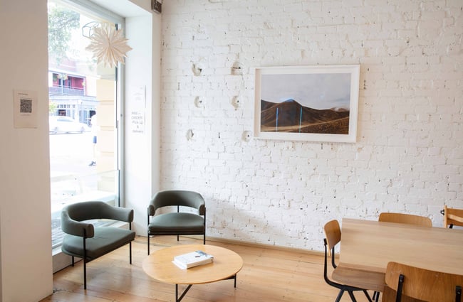 Tables and chairs in a corner inside a bright and sunny cafe.