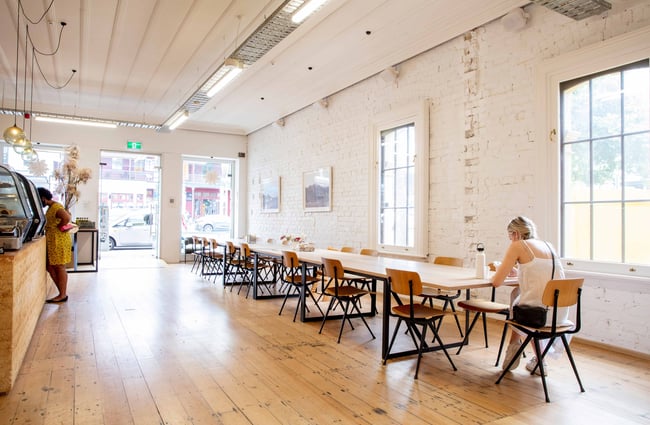 A female customer sitting at one end of a very long table.