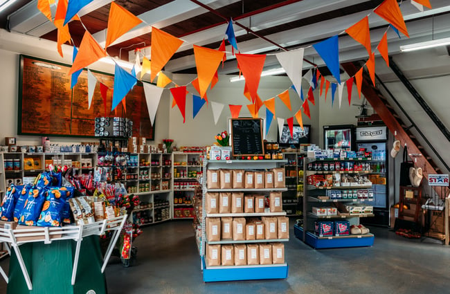 Rows of shelves with Dutch products in the market shop and orange, white and blue bunting up in De Molen.