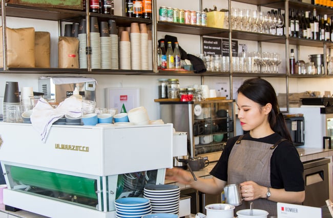Barista behind bar making coffee.