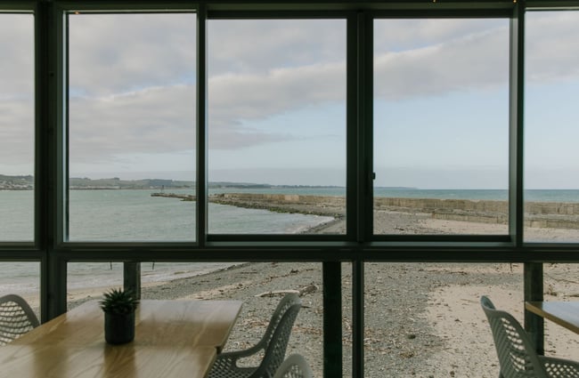 Looking out the big windows at Del Mar with a view of water and a beach.