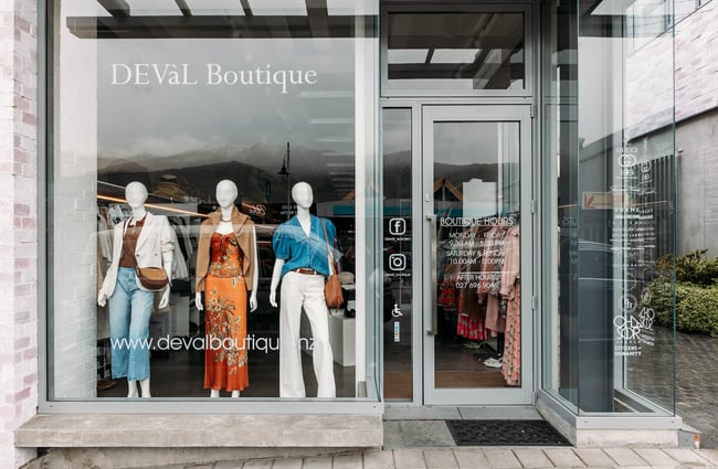The frontage of DEVàl Boutique, Wānaka, with three female mannequins in denim, white and orange outfits in the window display.