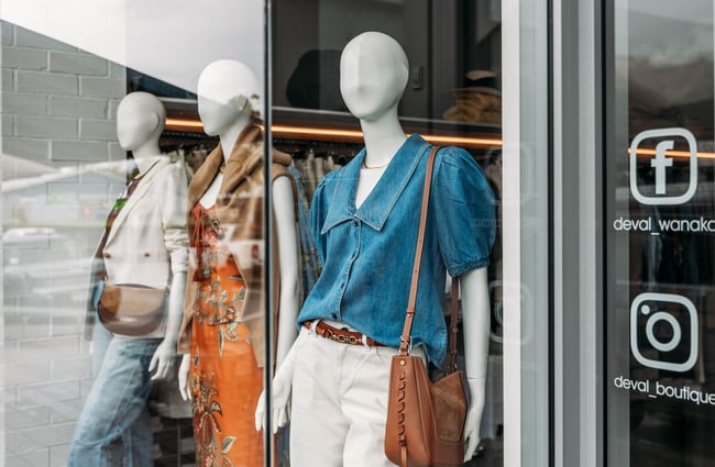 Three female mannequins in different outfits displayed in the street-side window in DEVàl Boutique, Wānaka.