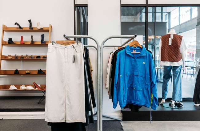 Racks of clothing with a shoe shelf behind at Different Avenue.