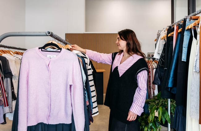 Shop manager hangs an item of clothing back on the rack at Different Avenue.