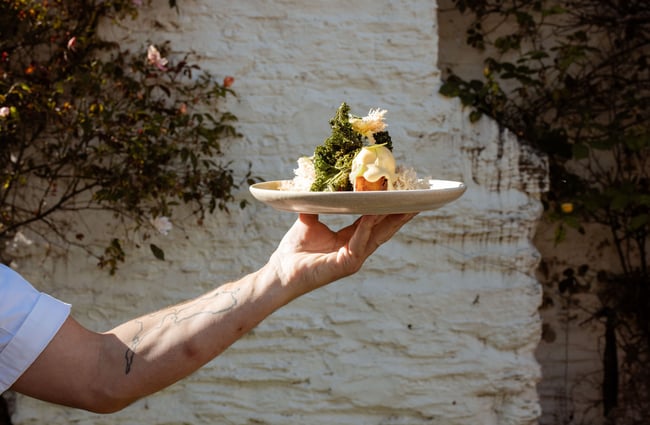 Someone holding up plate of eggs benedict at Dishery in Arrowtown Queenstown