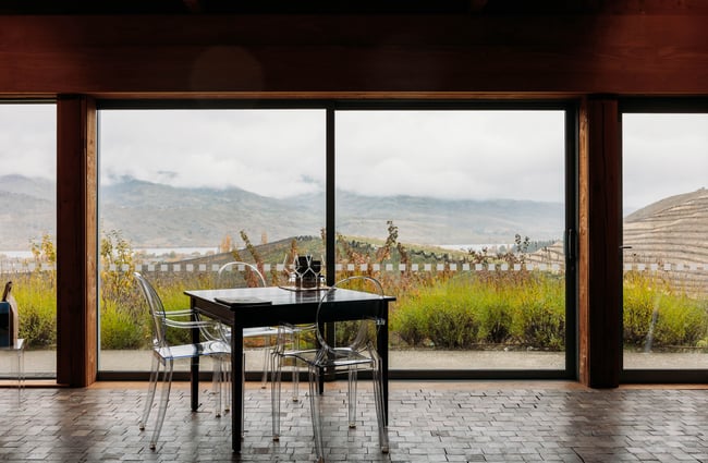Table and chairs in the window overlooking the landscape outside at Domaine-Thomson Wines Cellar Door.