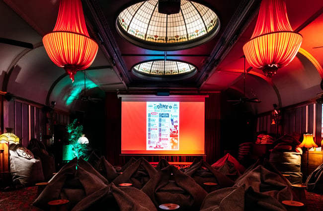 A large pull down screen in a dimly lit bar.