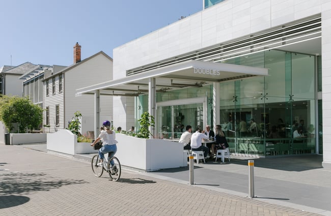 A cyclist biking past Doubles cafe on a sunny Christchurch day.