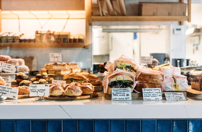 Close up of bakery cabinet filled with donuts, cream buns, sandwiches and more