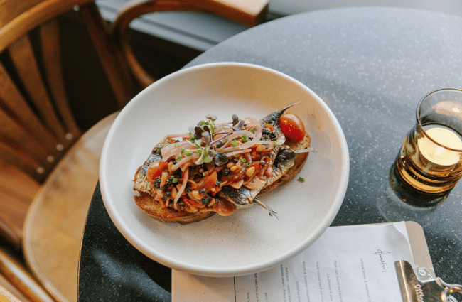 Image of a bread dish with a drink and menu next to it on table.