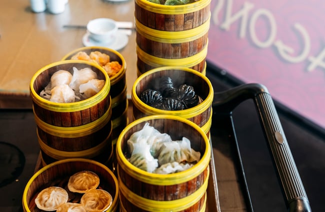 Stacks of bamboo steamer baskets with different types of dumplings inside each.