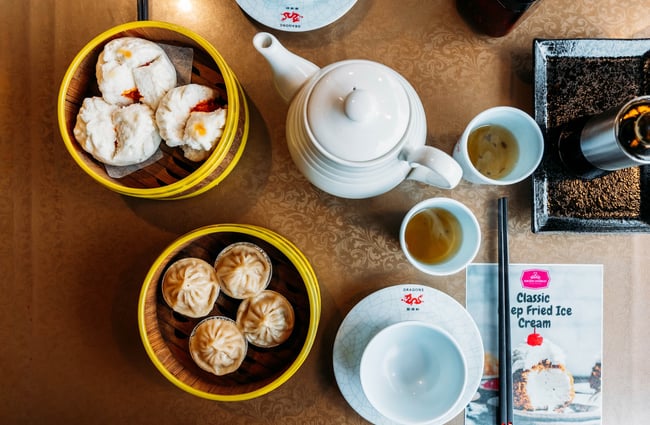 Flat lay of a table at Dragons with a teapot, little tea tumblers and dumplings in steamers.